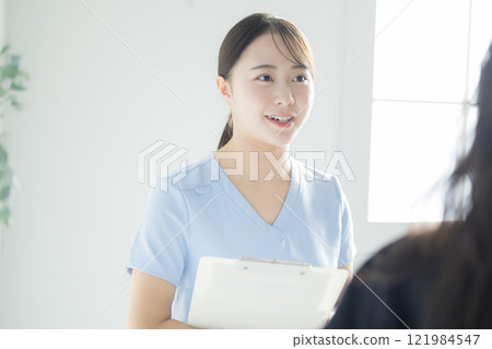 一名身穿白大褂的年輕女子，拿著病歷和活頁夾 121984547