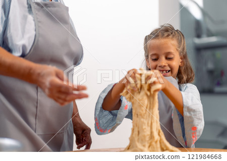 Happy girl kneading dough while baking with Happy girl kneading dough while baking with 121984668
