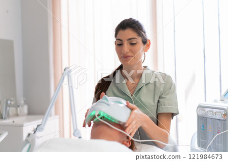 Smiling female cosmetologist placing hydrafacial Smiling female cosmetologist placing hydrafacial 121984673