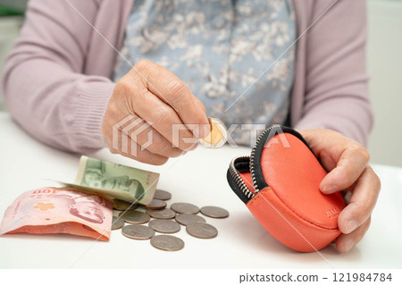 Asian senior or elderly old lady woman holding counting coin money in bag. Poverty, saving problem in retirement. Asian senior or elderly old lady woman holding counting coin money in bag. Poverty, saving problem in retirement. 121984784
