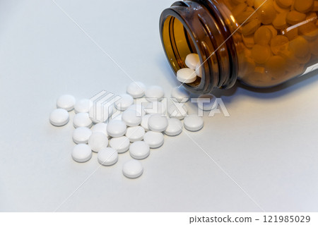White pills spilling out of a fallen glass bottle 121985029