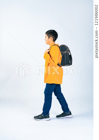 Elementary school boy walking with a school bag on his back 121986002