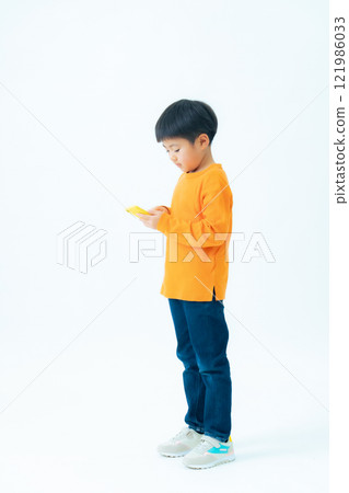 Full-body photo of a boy using a smartphone 121986033