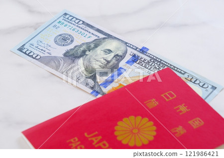 拿著日本護照和 100 美元鈔票計劃出國旅行的圖片。 121986421