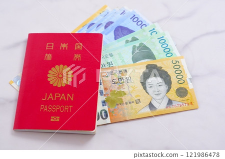 Korean currency, won (KRW) banknotes and a passport (10-year general passport, red), giving an image of a trip to Korea Korean currency, won (KRW) banknotes and a passport (10-year general passport, red), giving an image of a trip to Korea 121986478