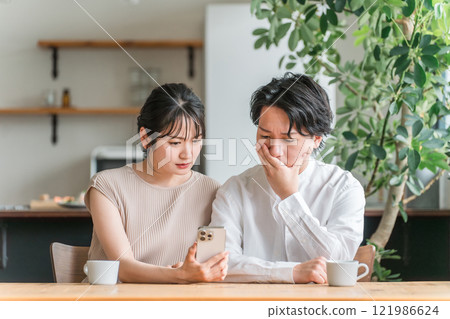 驚訝的夫妻在家裡看智慧型手機(新聞/投資/股票) 驚訝的夫妻在家裡看智慧型手機(新聞/投資/股票) 121986624