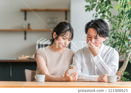 夫妻在家裡看智慧型手機時感到沮喪(驚訝、新聞、投資、股票) 夫妻在家裡看智慧型手機時感到沮喪(驚訝、新聞、投資、股票) 121986625