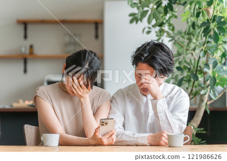 夫妻在家看智慧型手機時感到沮喪（新聞/投資/股票） 121986626