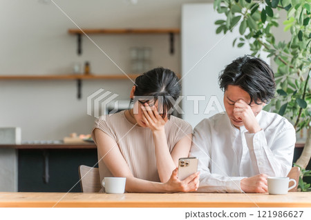 夫妻在家看智慧型手機時感到沮喪（新聞/投資/股票） 121986627