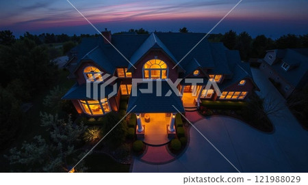 Beautiful Home Exterior at Dusk with Warm Interior Lighting and Lush Landscaping. 121988029