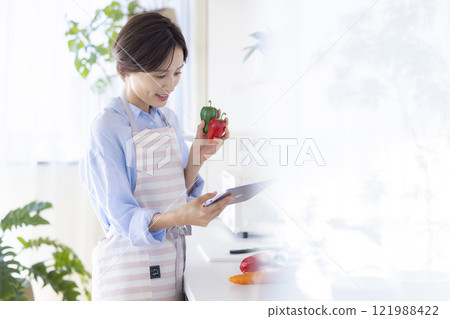 在廚房平板電腦上搜尋食譜的女人 在廚房平板電腦上搜尋食譜的女人 121988422