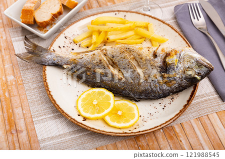 Baked fish called Dorada with French fries 121988545