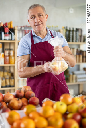 Mature salesman giving apples in grocery store 121988577