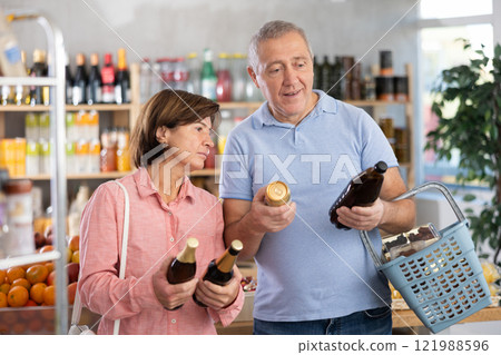 Senior couple hold bottle and choose consider alcohol beer in store 121988596