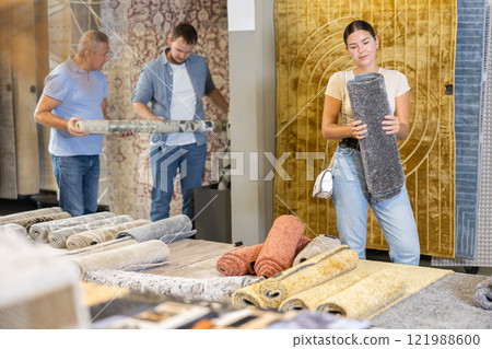 On territory of exhibition hall, girl inspect carpets On territory of exhibition hall, girl inspect carpets 121988600