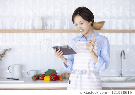 在廚房平板電腦上搜尋食譜的女人 在廚房平板電腦上搜尋食譜的女人 121988619