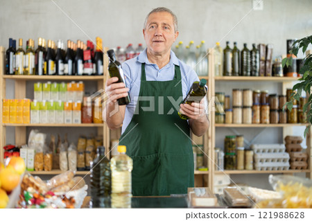 Elderly man seller offers olive oil in grocery store 121988628