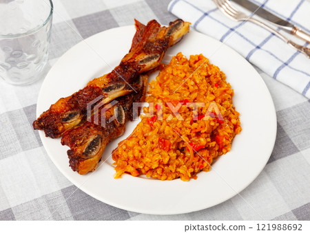 Delicious churrasco style grilled veal ribs served on plate with stewed cabbage with pearl barley porridge. Spain dish Delicious churrasco style grilled veal ribs served on plate with stewed cabbage with pearl barley porridge. Spain dish 121988692