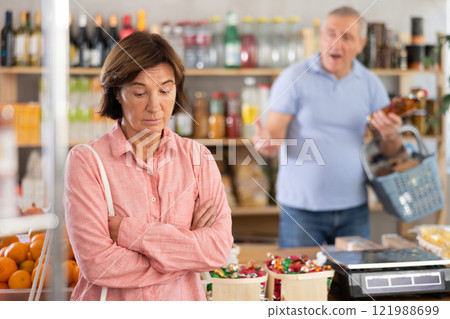 Senior husband stands behind pensioner wife and yells at companion Senior husband stands behind pensioner wife and yells at companion 121988699