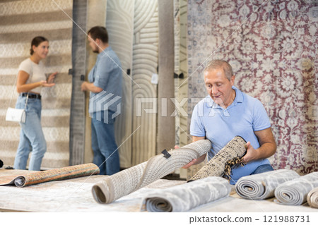 Elderly man chooses carpet in hardware store 121988731