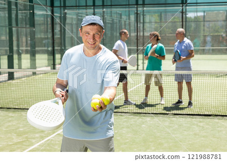 Adult man posing on padel tennis court Adult man posing on padel tennis court 121988781