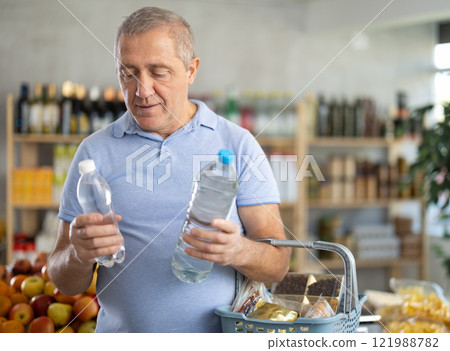 Elderly man choosing water in grocery store Elderly man choosing water in grocery store 121988782