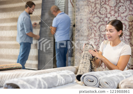 Young woman choosing carpet in building store 121988861
