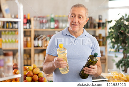 Mature man buyer looks thoughtfully at bottles of vegetable oil 121988913