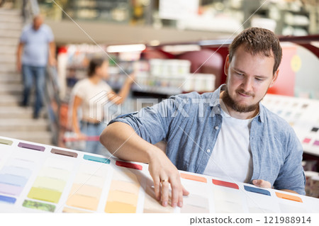Young man choosing paint sample in store 121988914