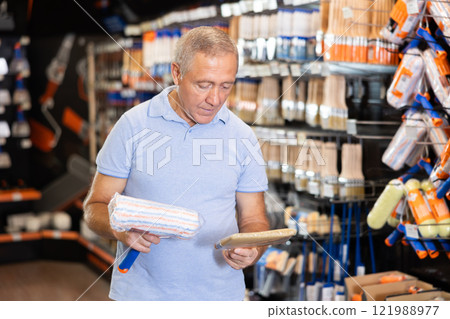 Senior man choose brush and painting roller and selects desired option 121988977