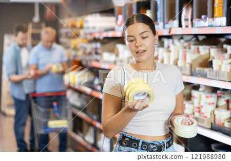 Young woman buy sticky adhesive tape in construction store for carrying out internal finishing work Young woman buy sticky adhesive tape in construction store for carrying out internal finishing work 121988980