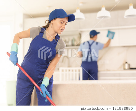 Cheerful girl from cleaning service washes floor in customer's house 121988990