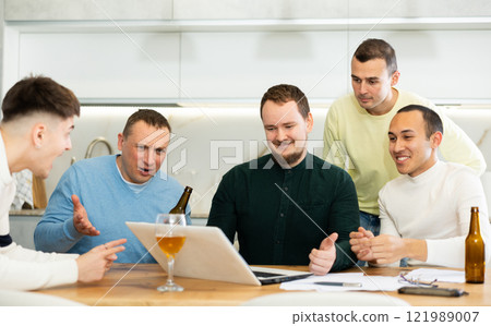 Group of football fans drinking beer and watching football match on laptop at home 121989007