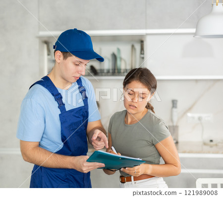 Male employee of repair team gives girl client documents . 121989008