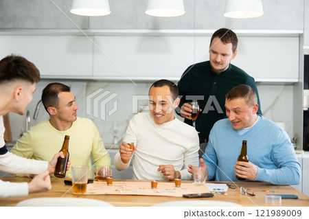 Cheerful men playing drinking board game at bachelor gathering Cheerful men playing drinking board game at bachelor gathering 121989009