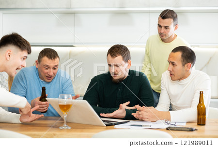 Worried male friends trying to solve problem together on laptop Worried male friends trying to solve problem together on laptop 121989011
