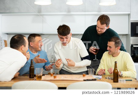 Friends drinking beer and enthusiastically playing board game at home Friends drinking beer and enthusiastically playing board game at home 121989026
