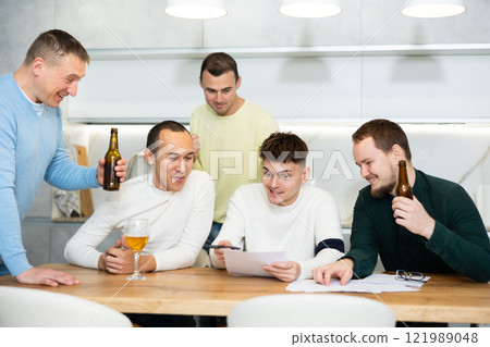 Brainstorming - male friends drinking beer and trying to solve financial problems by consulting each other while sitting at table Brainstorming - male friends drinking beer and trying to solve financial problems by consulting each other while sitting at table 121989048