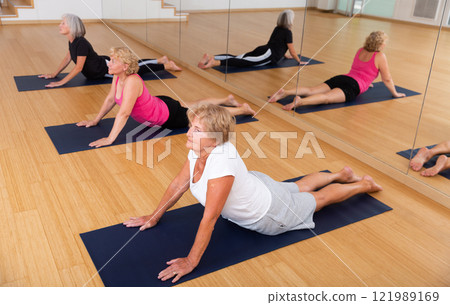 Senior woman doing Urdhva Mukha Shvanasana during group yoga workout 121989169