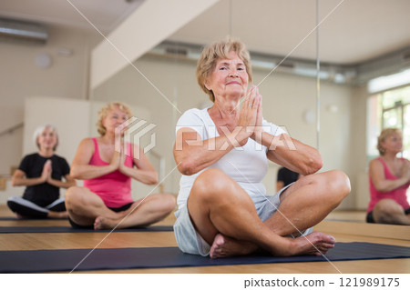 Group of mature women are doing yoga, sitting in the lotus position Group of mature women are doing yoga, sitting in the lotus position 121989175