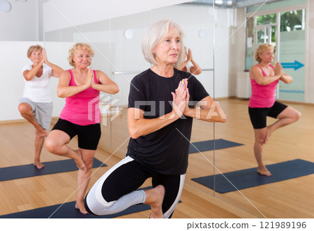 Aged women perform the exercise while standing in the tree pose 121989196