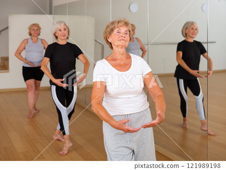Elderly woman practicing ballet dance moves in choreographic studio Elderly woman practicing ballet dance moves in choreographic studio 121989198