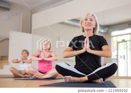 Senior women sitting in lotus pose during group training 121989202