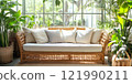 A beautiful indoor rattan couch surrounded by lush green plants creates a calming atmosphere. This cozy seating adds warmth to any space. Perfect for relaxation or social gatherings. AI 121990211