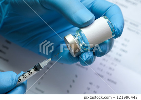 doctor's hand holds a syringe and a blue vaccine bottle at the hospital. Health and medical concepts. 121990442