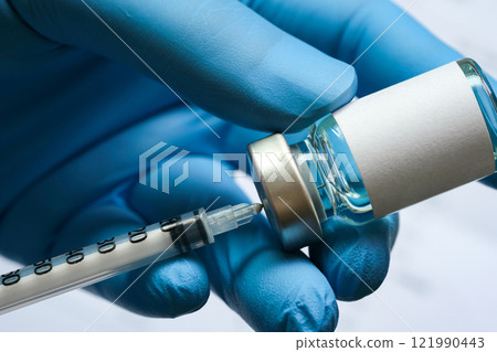 doctor's hand holds a syringe and a blue vaccine bottle at the hospital. Health and medical concepts. doctor's hand holds a syringe and a blue vaccine bottle at the hospital. Health and medical concepts. 121990443