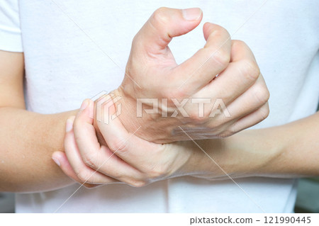 The young man touched his wrist with his hand. And he had bone and wrist pain. from hard work The young man touched his wrist with his hand. And he had bone and wrist pain. from hard work 121990445