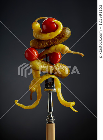 Canned yellow peppers, cucumbers, and tomatoes on a black background. 121991152