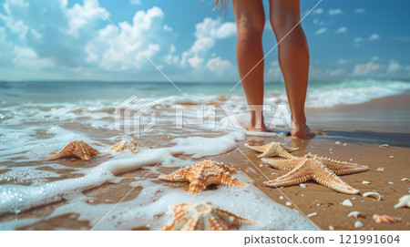 Legs walking through ocean waves with starfish on sandy shore 121991604