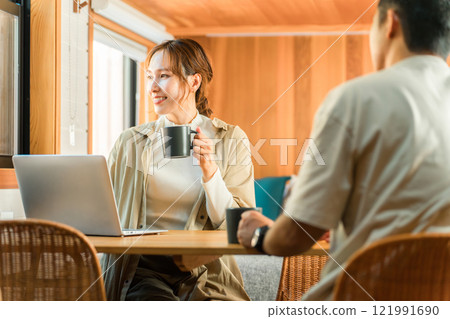 Couple, man and woman (talking, conversation) drinking coffee while using a computer at home, villa, cottage 121991690